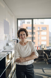 Successful businesswoman standing in her office with arms crossed - KNSF04400