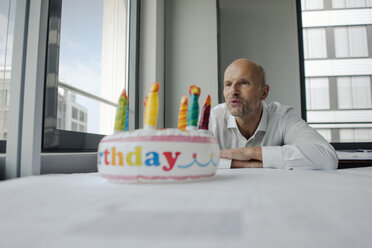 Geschäftsmann feiert seinen Geburtstag im Büro und bläst die Kerzen aus - KNSF04415
