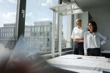 Two architects standing in office, looking out of window - KNSF04455