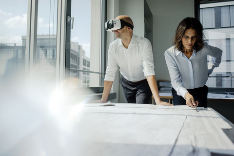 Zwei Architekten arbeiten an Entwürfen, Mann mit VR-Brille, lizenzfreies Stockfoto