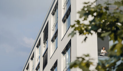 Frau schaut aus dem Bürofenster - KNSF04482