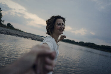 Laughing woman holding hands at the river - KNSF04483