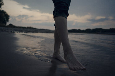 Woman walking barefoot in river, low section - KNSF04484