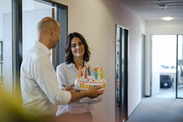 Businessman gifting his colleague with a birthday cake in office - KNSF04522