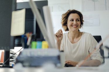 Businesswoman working in office, sitting at desk - KNSF04557