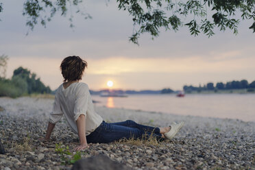 Woman sitting at the river, watching sunset - KNSF04583