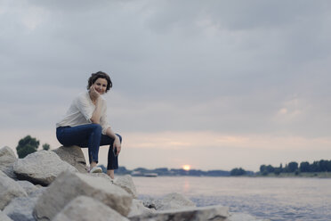 Frau sitzt am Fluss und beobachtet den Sonnenuntergang - KNSF04587