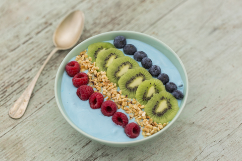 Smoothie-Bowl mit Heidelbeeren, Himbeeren, Kiwi und gehackten Haselnüssen, lizenzfreies Stockfoto