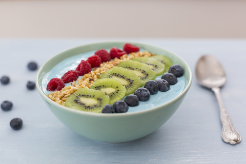 Smoothie-Bowl mit Heidelbeeren, Himbeeren, Kiwi und gehackten Haselnüssen, lizenzfreies Stockfoto