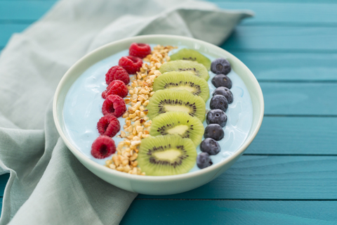 Smoothie-Bowl mit Heidelbeeren, Himbeeren, Kiwi und gehackten Haselnüssen, lizenzfreies Stockfoto