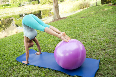 Frau macht Yoga und Pilates-Übungen auf einer Matte im Freien - AURF02218