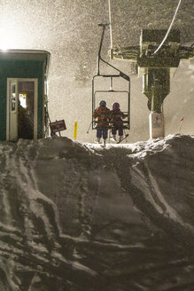 Zwei Mädchen fahren beim Nachtskilauf mit dem Skilift, Silverton, Colorado. - AURF02244