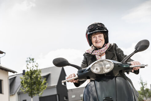 Aktive ältere Dame beim Motorrollerfahren in der Stadt - UUF14915