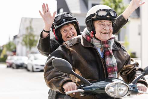 Glückliches älteres Paar hat Spaß, fährt Motorroller und winkt - UUF14920