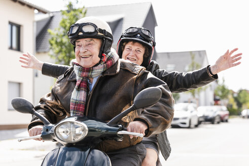 Glückliches älteres Paar hat Spaß, fährt Motorroller und winkt - UUF14921