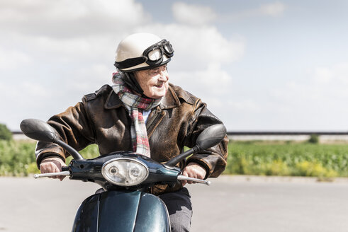 Aktiver älterer Mann, der mit seinem Motorroller zu schnell fährt - UUF14925