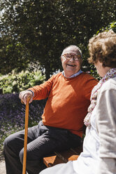 Senior couple sitting on bench in a park, talking - UUF14942