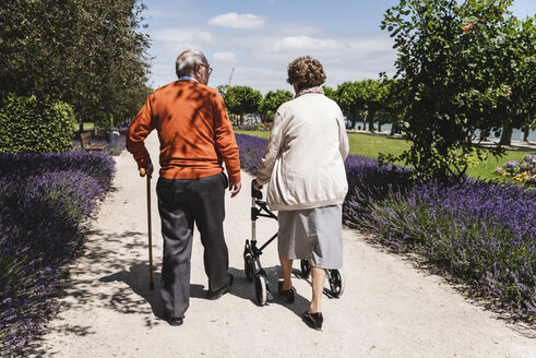 Älteres Paar geht im Park spazieren, die Frau benutzt eine Gehhilfe auf Rädern - UUF14946