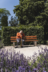 Älterer Mann sitzt auf einer Parkbank und wartet - UUF14950