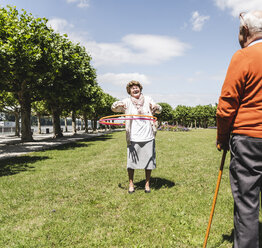 Senior watching elderly lady playing with a hoola hoop - UUF14952