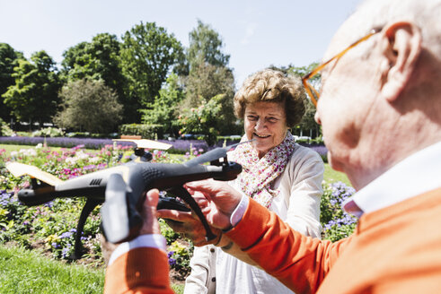 Älteres Paar spielt mit einer Drohne im Park - UUF14955