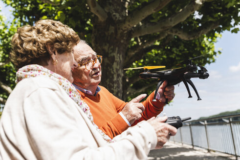 Älteres Paar spielt mit einer Drohne im Park - UUF14956