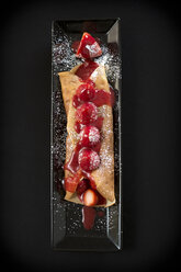 Crepes are adorned with fresh strawberries, blackberries, coulis, whipped cream, and sugar. - AURF02325