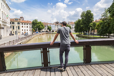 Italien, Venetien, Treviso, Tourist schaut auf Fluss - JUNF01137