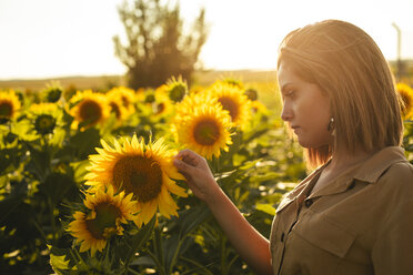 Porträt einer jungen Frau in einem Sonnenblumenfeld - ACPF00294