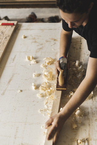 Zimmermann beim Hobeln eines Holzstücks in der Werkstatt, lizenzfreies Stockfoto