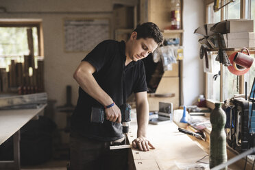 Carpenter using drill on piece of wood in workshop - PSIF00049