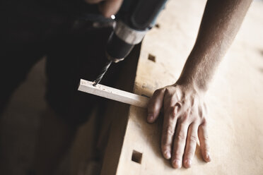 Close-up of carpenter using drill on piece of wood in workshop - PSIF00050