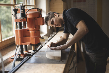 Schreiner sägt ein Stück Holz in der Werkstatt - PSIF00051