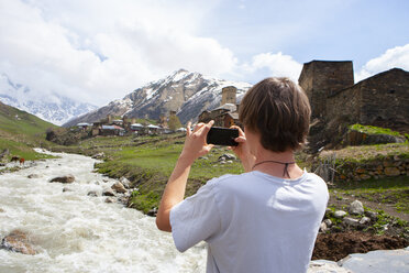 Georgia, Ushguli, Photographer taking pictures of the historic denfense towers made from stone - WWF04340