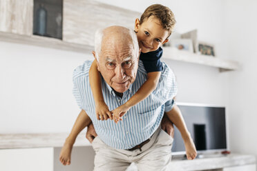 Portrait of grandfather giving his grandson a piggyback ride in the living room - JRFF01816