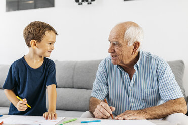 Grandfather and grandson drawing together with coloured pencils at home - JRFF01819