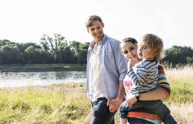 Glückliche Familie bei einem Spaziergang am Flussufer an einem schönen Sommertag - UUF14961