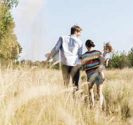 Glückliche Familie bei einem Spaziergang am Flussufer an einem schönen Sommertag - UUF14963