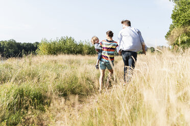 Glückliche Familie bei einem Spaziergang am Flussufer an einem schönen Sommertag - UUF14964