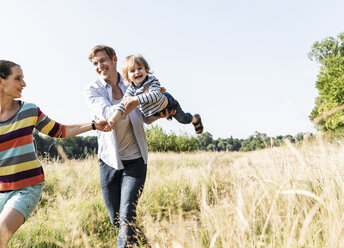 Glückliche Familie bei einem Spaziergang am Flussufer an einem schönen Sommertag - UUF14970