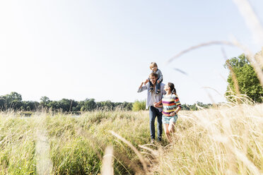 Glückliche Familie bei einem Spaziergang am Flussufer an einem schönen Sommertag - UUF14976