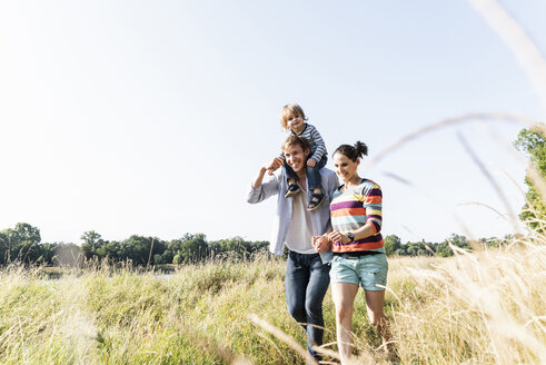 Glückliche Familie bei einem Spaziergang am Flussufer an einem schönen Sommertag - UUF14977