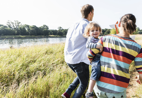 Glückliche Familie bei einem Spaziergang am Flussufer an einem schönen Sommertag, lizenzfreies Stockfoto