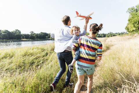 Glückliche Familie bei einem Spaziergang am Flussufer an einem schönen Sommertag, lizenzfreies Stockfoto