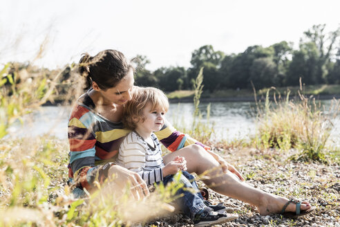 Mutter und Sohn sitzen am Flussufer - UUF14988