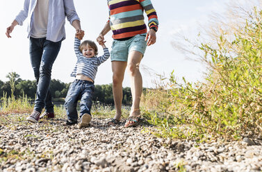 Glückliche Familie bei einem Spaziergang am Flussufer an einem schönen Sommertag - UUF14996