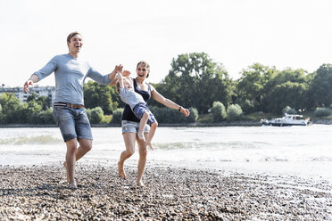 Glückliche Familie bei einem Spaziergang am Flussufer an einem schönen Sommertag - UUF15004