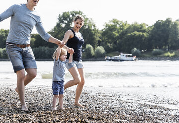 Glückliche Familie bei einem Spaziergang am Flussufer an einem schönen Sommertag - UUF15005