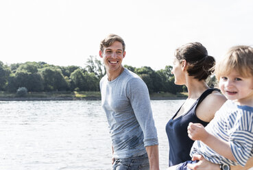 Glückliche Familie bei einem Spaziergang am Flussufer an einem schönen Sommertag - UUF15009