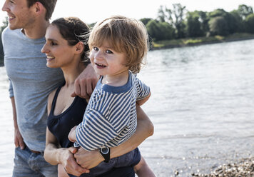 Glückliche Familie bei einem Spaziergang am Flussufer an einem schönen Sommertag - UUF15010